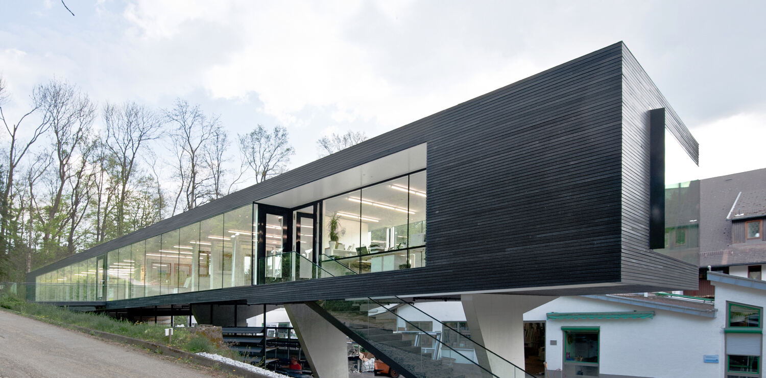Firmengebäude von naturfenster mit schwarzer Holzfassade und großen Glasflächen